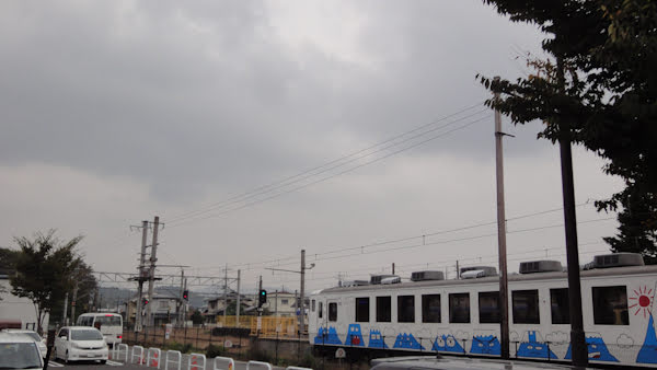 a cloudy sky over a train with cartoon versions of mt fuji painted on it